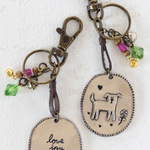 Two keychains with oval tags and metal clasps on a white background