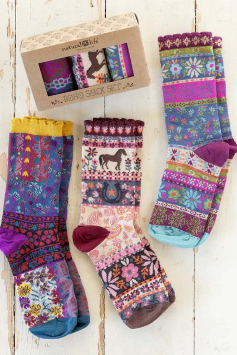Colorful patterned socks with a box of additional socks on a wooden surface
