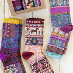 Colorful patterned socks with a box of additional socks on a wooden surface