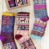 Colorful patterned socks with a box of additional socks on a wooden surface