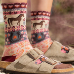 Person wearing patterned socks with horse design and sandals on a natural background