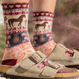 Person wearing patterned socks with horse design and sandals on a natural background