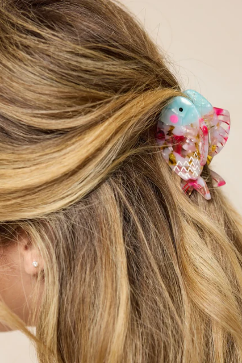 Decorative fish hair clip in a person's hair with a plain background