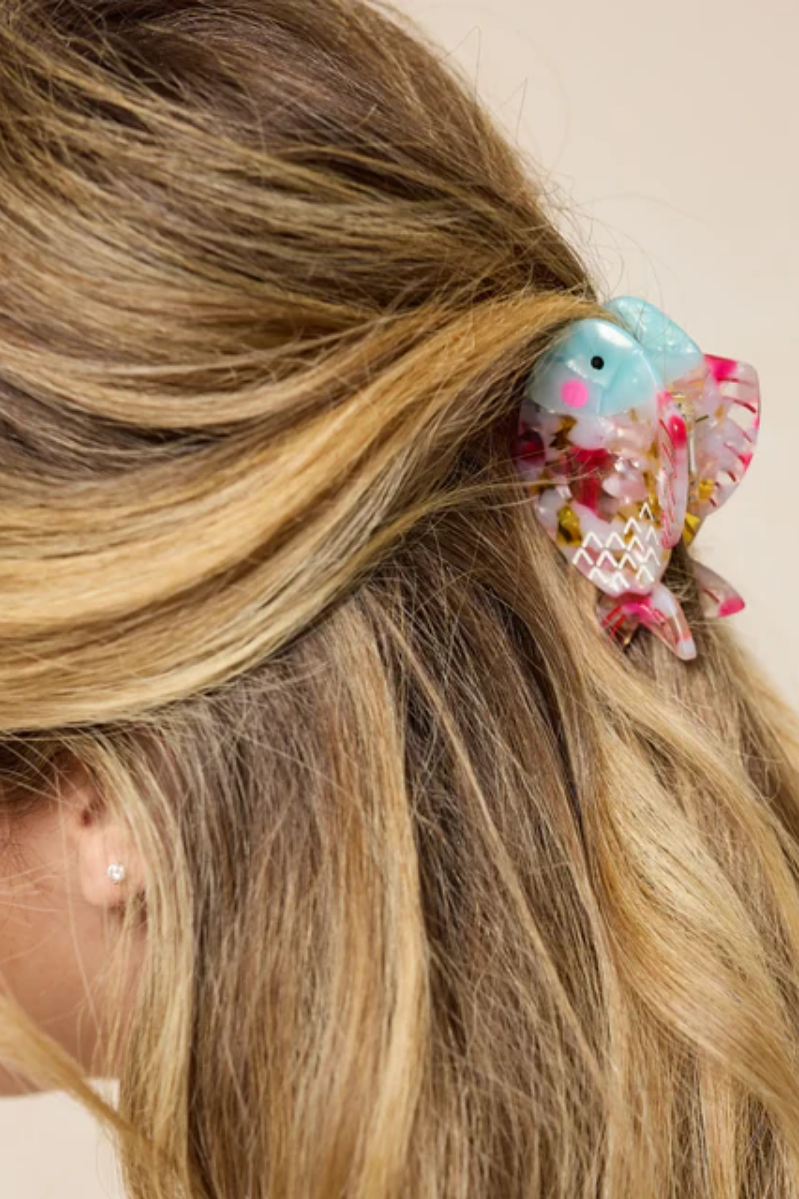 Decorative fish hair clip in a person's hair with a plain background