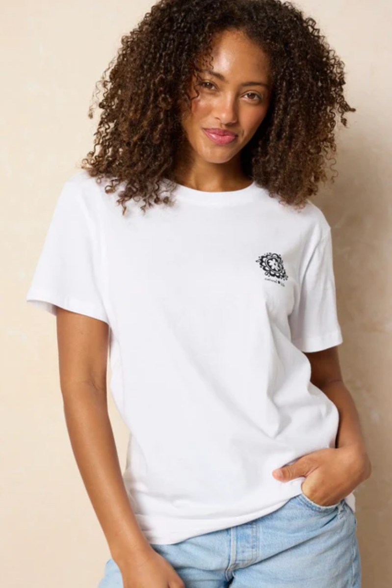 Woman wearing a white t-shirt with a small logo on a beige background