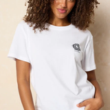 Woman wearing a white t-shirt with a small logo on a beige background