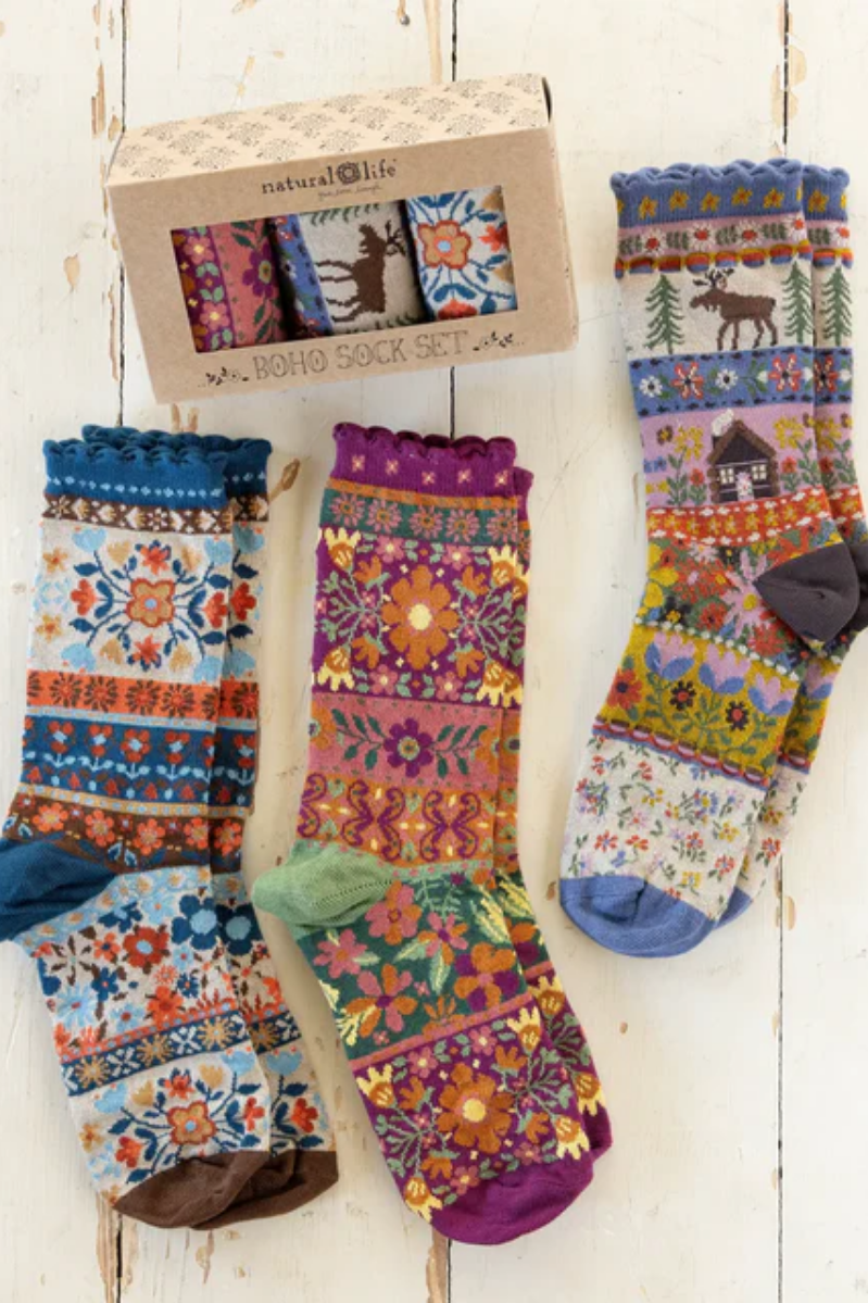 Colorful patterned socks displayed on a wooden stand with packaging in the background.