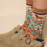 Patterned socks with a horse design worn with beige boots on a neutral background