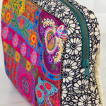 Colorful floral and geometric patterned pouch with a zipper on a white background