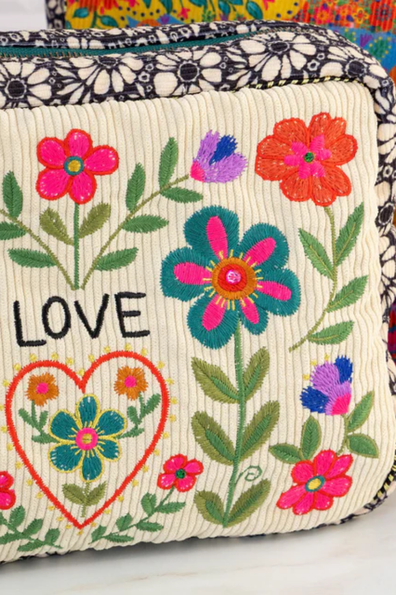 Embroidered fabric with flowers, a heart, and the word 'LOVE' on a colorful background.