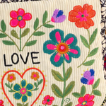 Embroidered fabric with flowers, a heart, and the word 'LOVE' on a colorful background.
