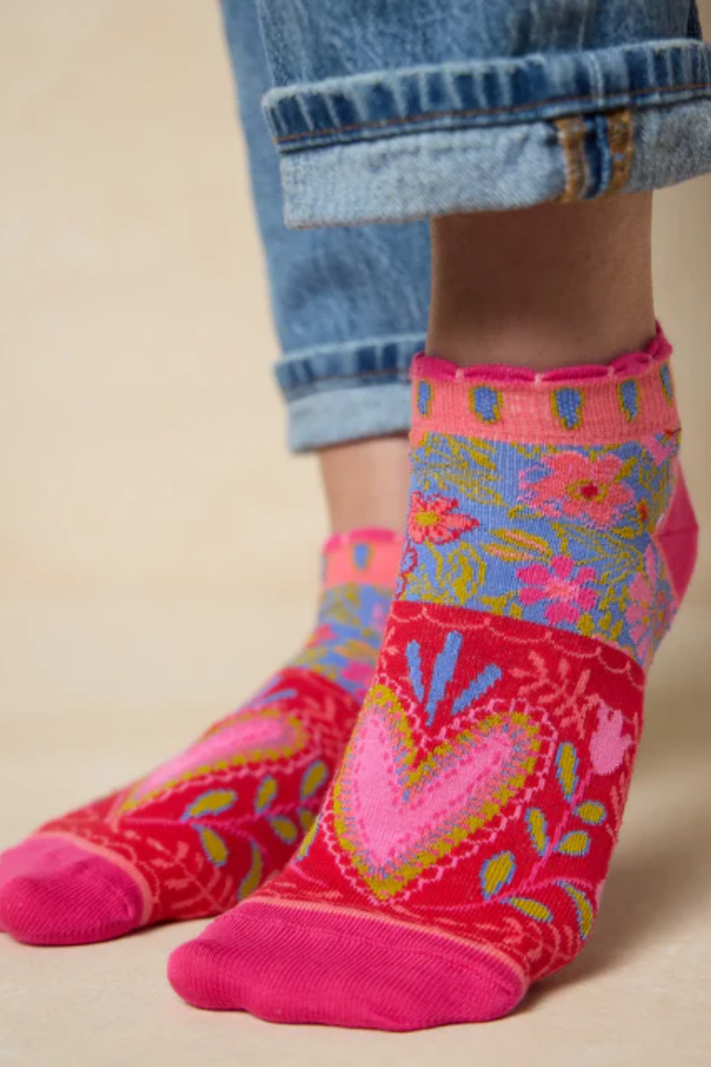 Colorful floral-patterned socks worn with rolled-up jeans on a beige background