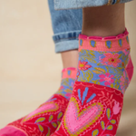 Colorful floral-patterned socks worn with rolled-up jeans on a beige background