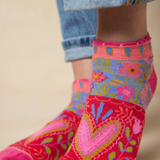 Colorful floral-patterned socks worn with rolled-up jeans on a beige background