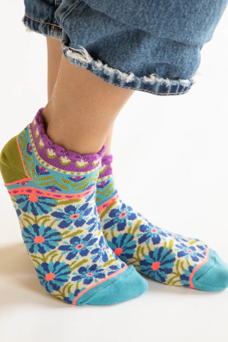 Colorful patterned socks worn with denim jeans on a white background