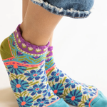 Colorful patterned socks worn with denim jeans on a white background