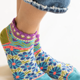 Colorful patterned socks worn with denim jeans on a white background