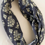 Black infinity scarf with yellow floral pattern on a white background