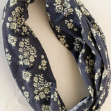 Black infinity scarf with yellow floral pattern on a white background