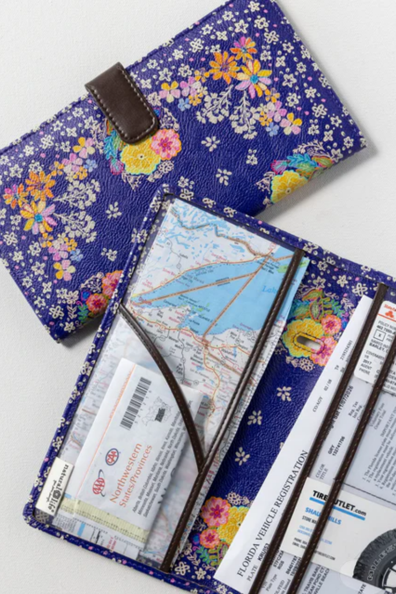 Floral-patterned travel wallet with maps and tickets on a white background
