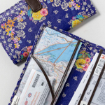Floral-patterned travel wallet with maps and tickets on a white background