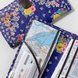 Floral-patterned travel wallet with maps and tickets on a white background