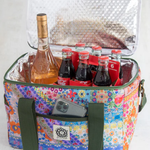 Colorful floral-patterned cooler bag with bottles and a phone inside on a white background