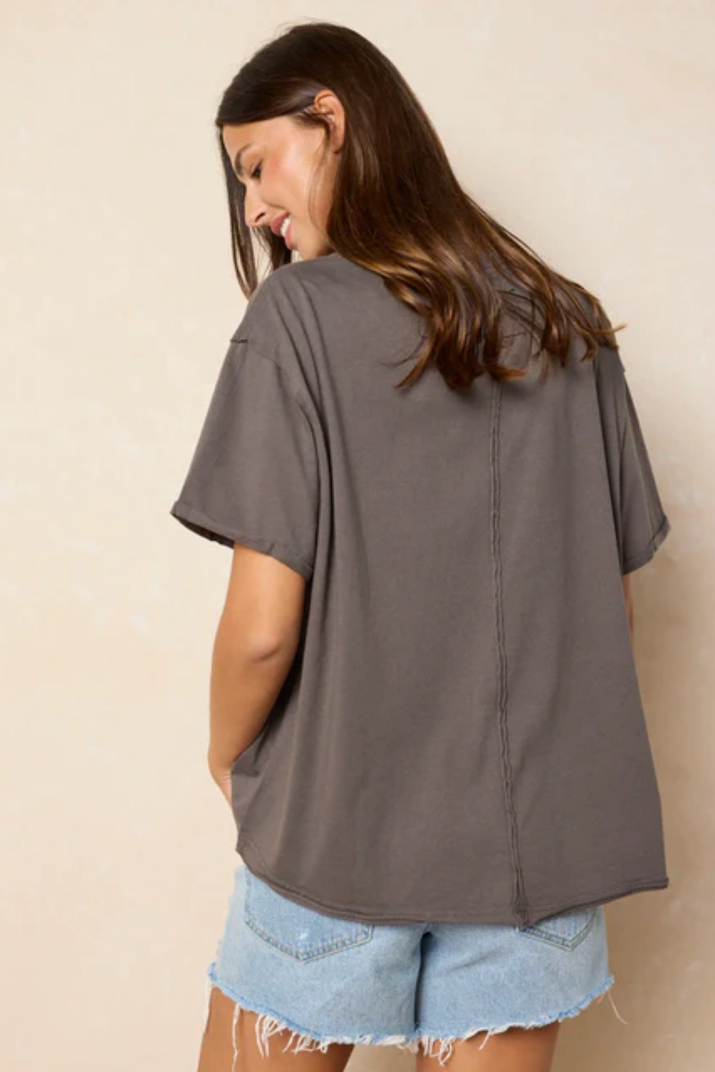 Woman wearing a gray oversized t-shirt and denim shorts against a beige background