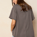 Woman wearing a gray oversized t-shirt and denim shorts against a beige background