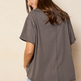 Woman wearing a gray oversized t-shirt and denim shorts against a beige background