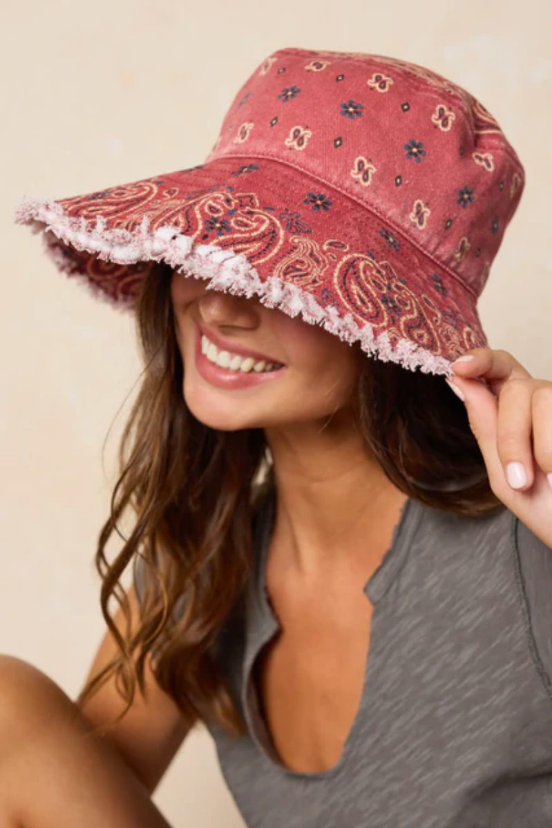 Woman wearing a red patterned bucket hat against a beige background