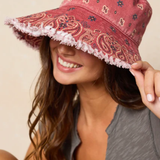 Woman wearing a red patterned bucket hat against a beige background