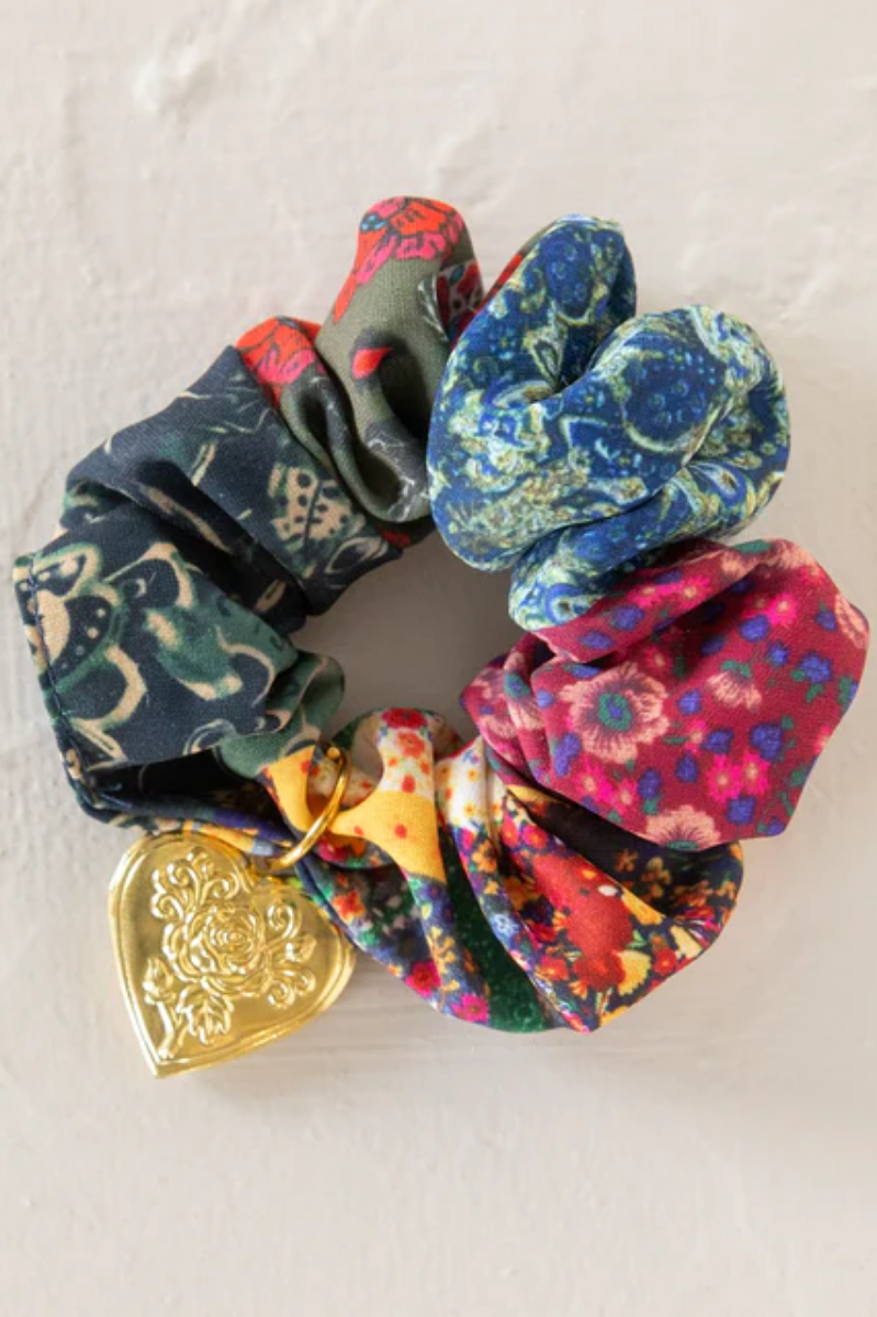 Colorful scrunchies with a gold heart-shaped charm on a light background