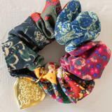 Colorful scrunchies with a gold heart-shaped charm on a light background