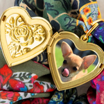 Heart-shaped locket with a dog's reflection on a colorful fabric background
