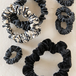 Set of black and patterned scrunchies on a light background