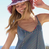 Woman wearing a red patterned hat and blue checkered dress outdoors.