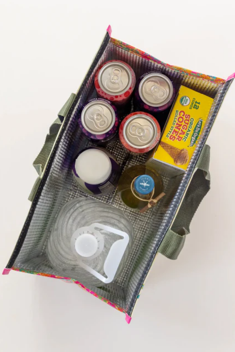 Assorted items including jars, a box of cookies, and a tumbler in a green bag on a white background