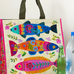 Colorful fish-patterned bag with two bottles on a wooden surface