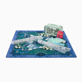Board game set with a blue mat, dice, and game pieces on a white background