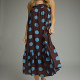 Woman wearing a brown dress with blue polka dots against a gray background