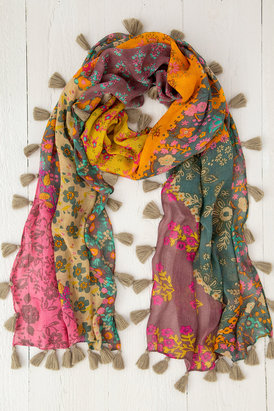 Multicolored floral scarf with tassels on a white wooden background