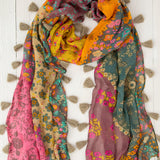 Multicolored floral scarf with tassels on a white wooden background