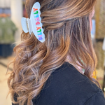 Woman wearing a hairclip with her hair pulled half up and half down Hair Clip says, "Dilly Dally."