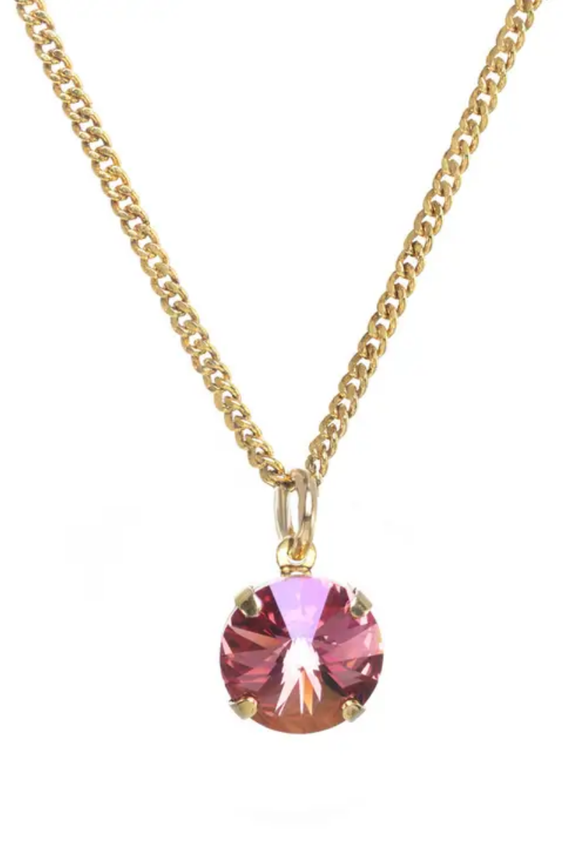 Gold necklace with a pink gemstone pendant on a white background