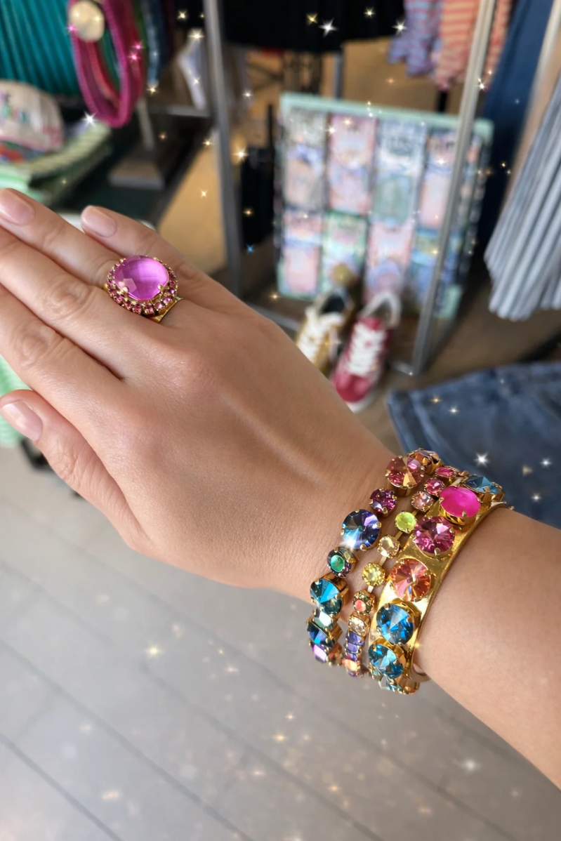 Hand wearing a colorful bracelet and purple gemstone ring with a blurred store background