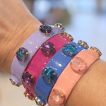 Colorful bracelets with gemstones on a wrist against a blurred background