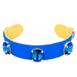 Blue cuff bracelet with gold accents and blue gemstones on a white background