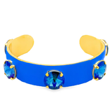 Blue cuff bracelet with gold accents and blue gemstones on a white background