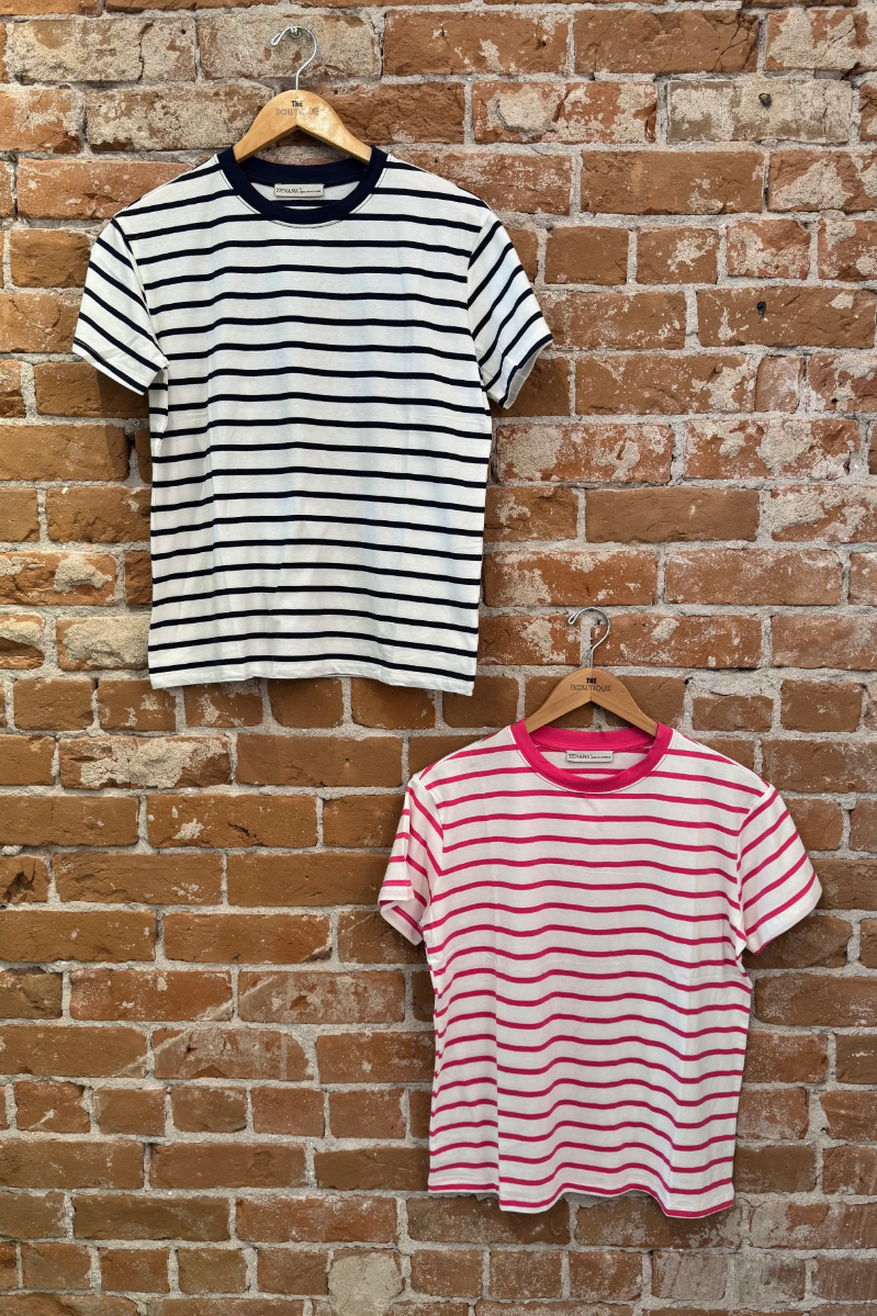 Two striped t-shirts hanging on wooden hangers against a brick wall.
